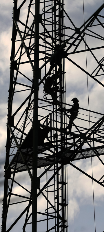 Workers are climbing to repair the telecommunication tower or poles, in the evening